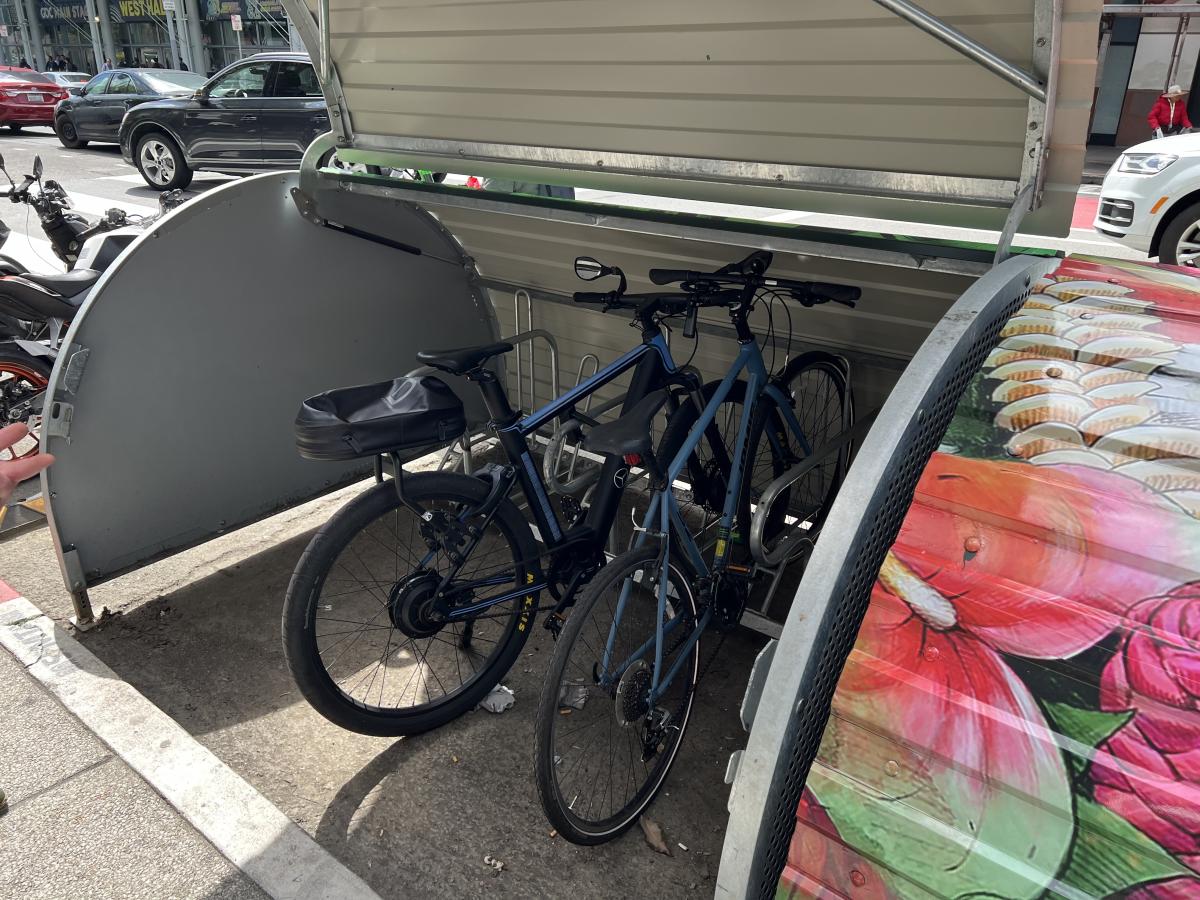 SFMTA’s new bikehangar at 4th & Minna streets with bikehangar door open & two bikes parked inside. 