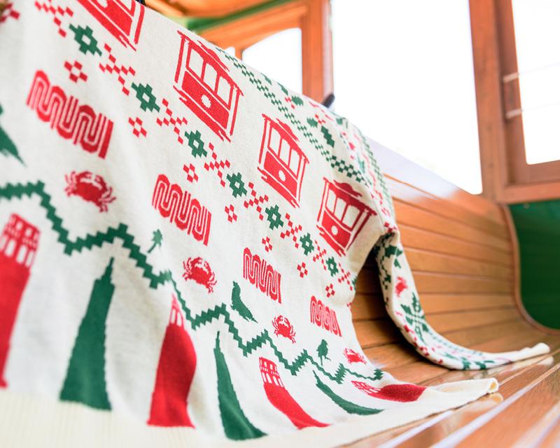 Muni holiday sweater with red, green and cream colors placed on the wooden seat of one of our vehicles.