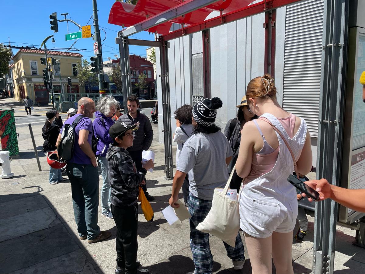 Several people wait at a bus stop. 