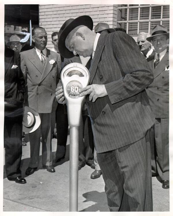 Mayor Roger D. Lapham tests a parking meter as a crowd looks on in San Francisco. Vintage photo from 1947.