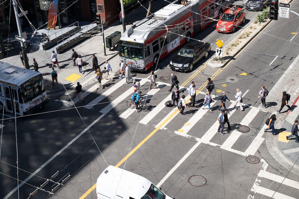 Aerial view of several people crossing a downtown San Francisco intersection. 