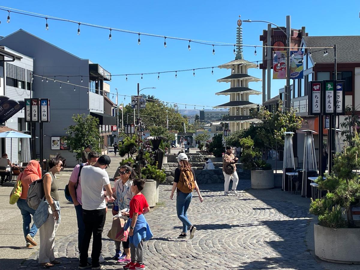 People stand and walk in a plaza in Japantown. 