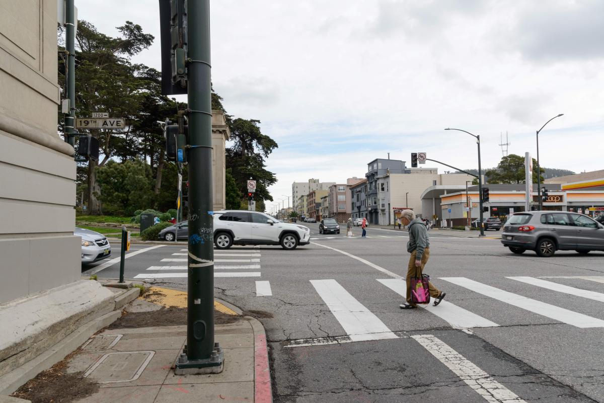 Person walks across the street at a major intersection near Golden Gate Park.