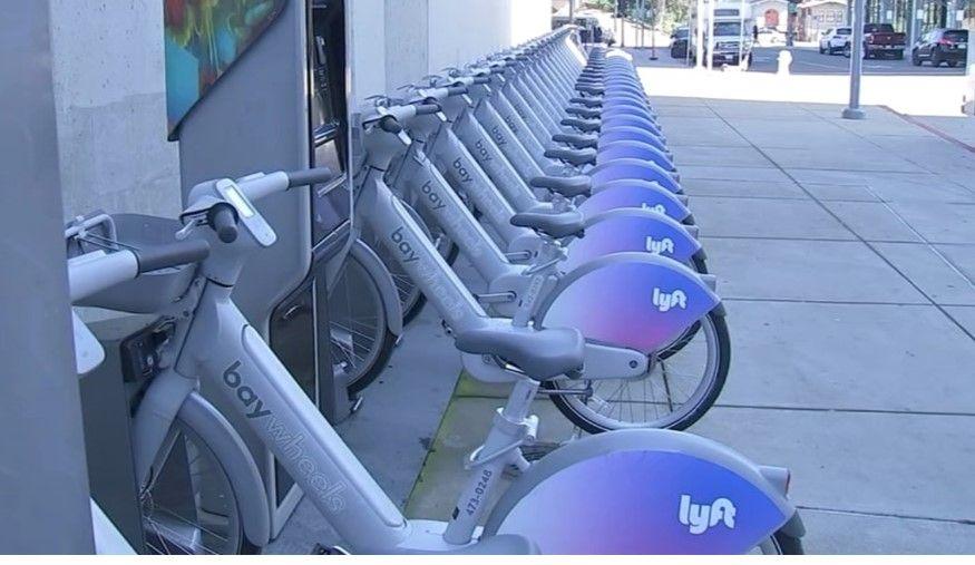 Bikeshare station full of the same type of gray bike. 