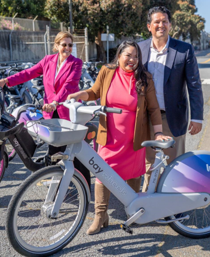 Daly City Mayor Juslyn Manalo and others smile at a new bikeshare station at Daly City BART.