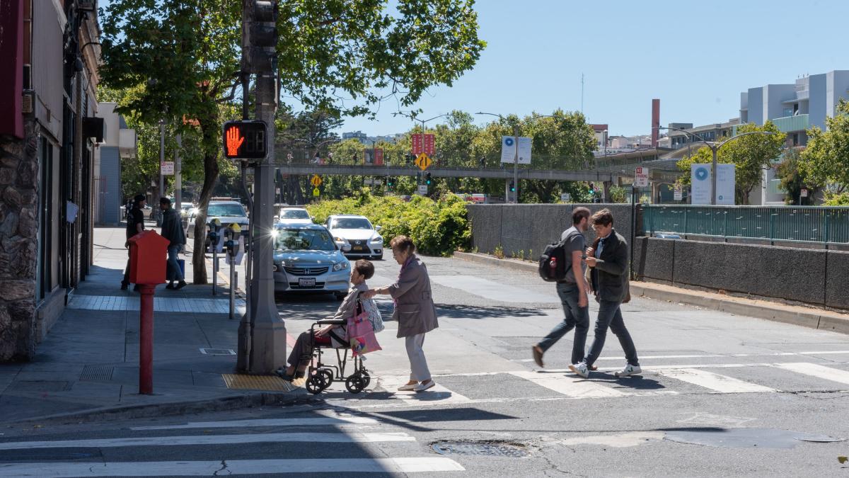 People cross the street on Geary Boulevard.