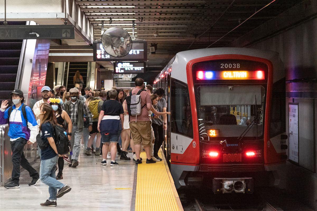 People board a train from a Muni station platform. 