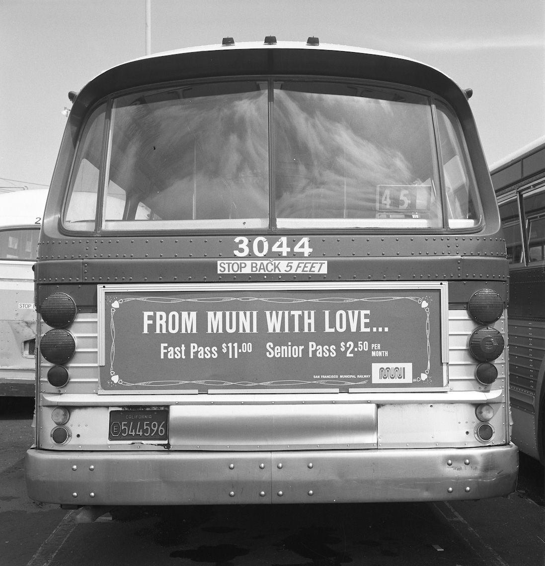 Archival image in black and white of the back of a Muni bus. An advertisement on the back of the bus says: "From Muni with Love."