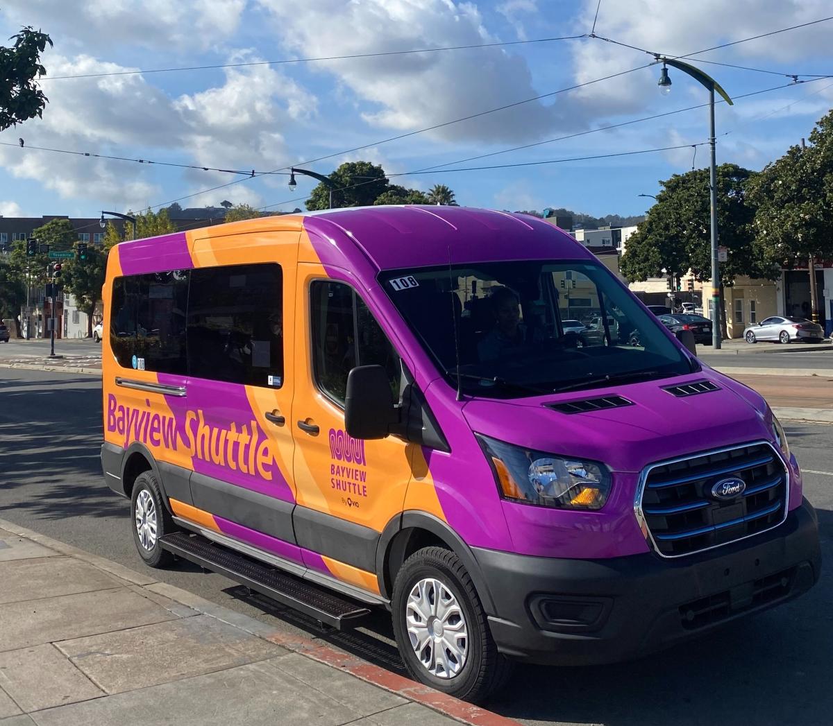 Photo of a new Bayview Shuttle vehicle. It's light orange and purple in color with large font that says Bayview Shuttle.