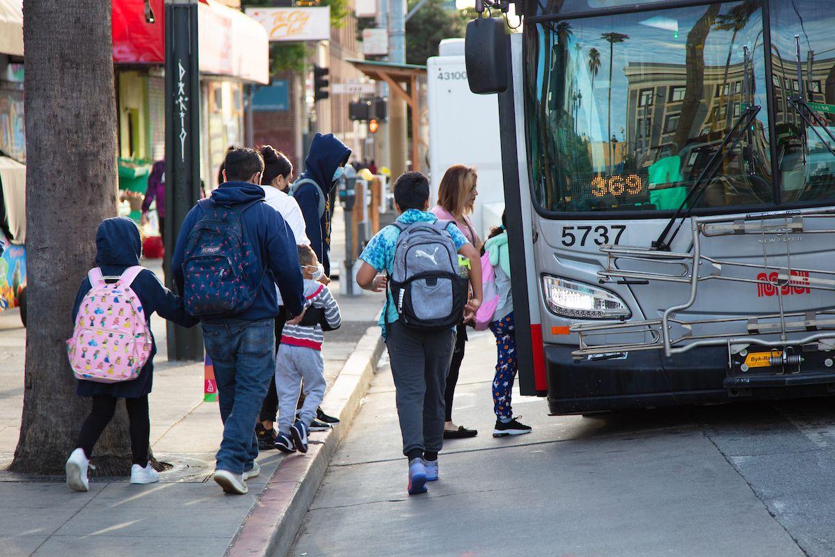 Several people walk toward a Muni bus to board. 