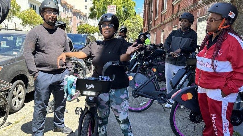 Several people wearing bike helmets pose for a photo during a bike ride hosted by The New Community Leadership Foundation.