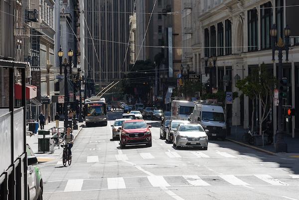Sutter Street Looking to the east down Sutter Street Cars in both travel lanes approaching a crosswalk, a biker in the bus lane approaching as well , a bus in the background in the bus lane.