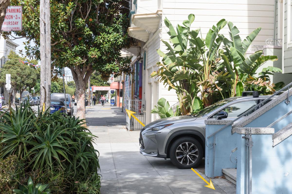 Image shows a gray car parked illegally in a driveway because the car goes over part of the sidewalk, illustrated by a yellow arrow beside the car.