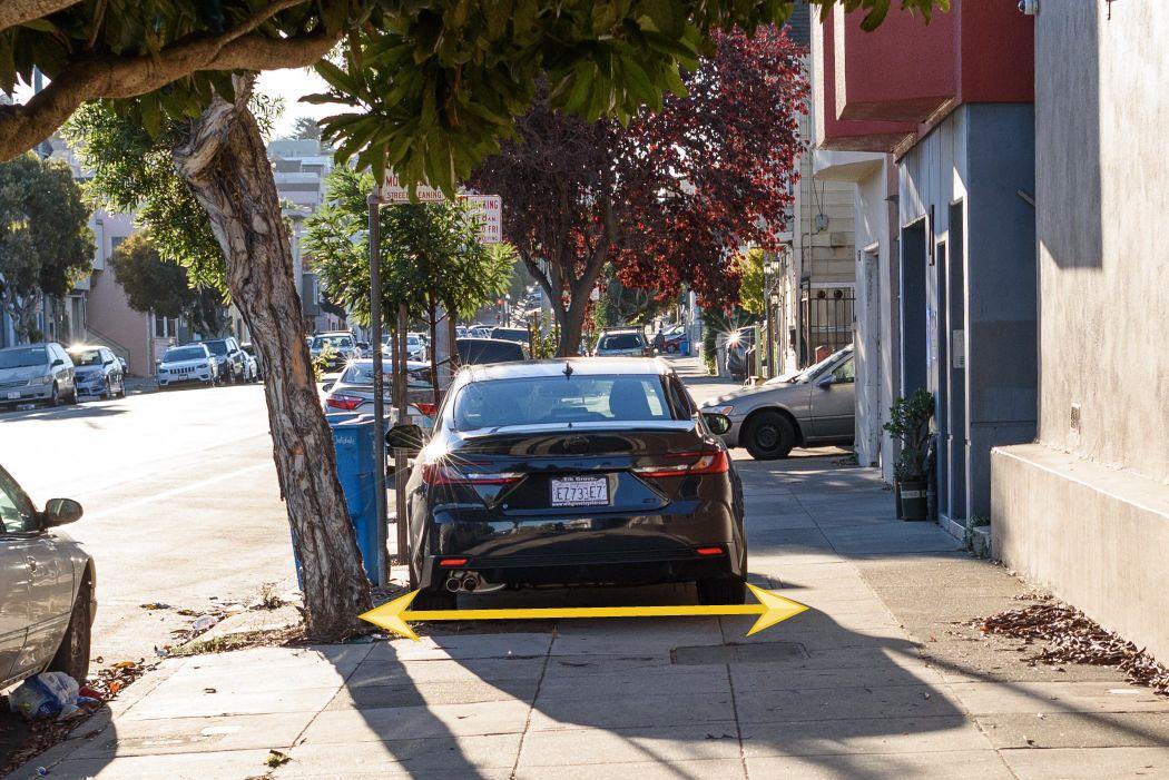 Image shows a vehicle parked entirely on a sidewalk, demonstrated by a yellow arrow drawn behind the car.