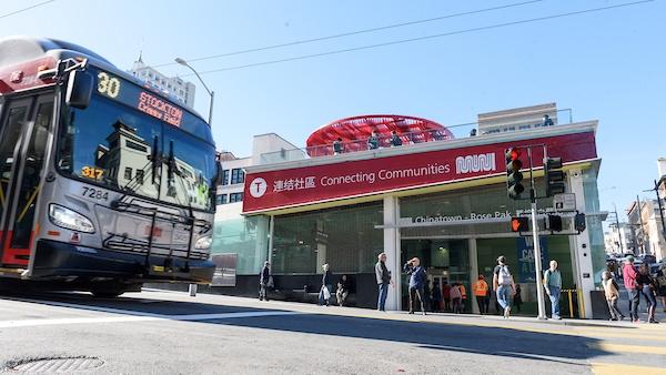 30 Stockton bus nears Chinatown-Rose Pak Station as people stand on the sidewalk in the background.