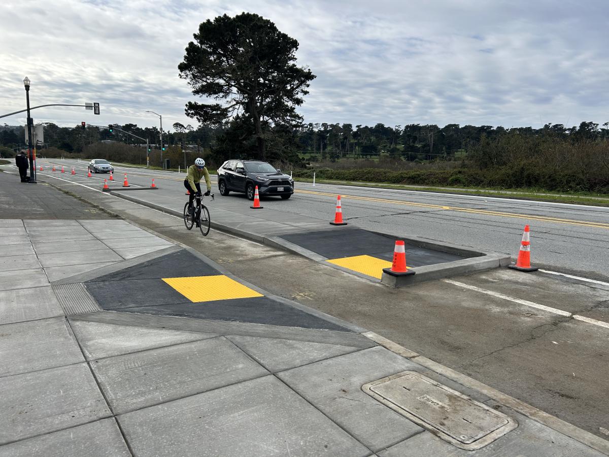 Bicyclist on completed bikeway protected by transit boarding island 