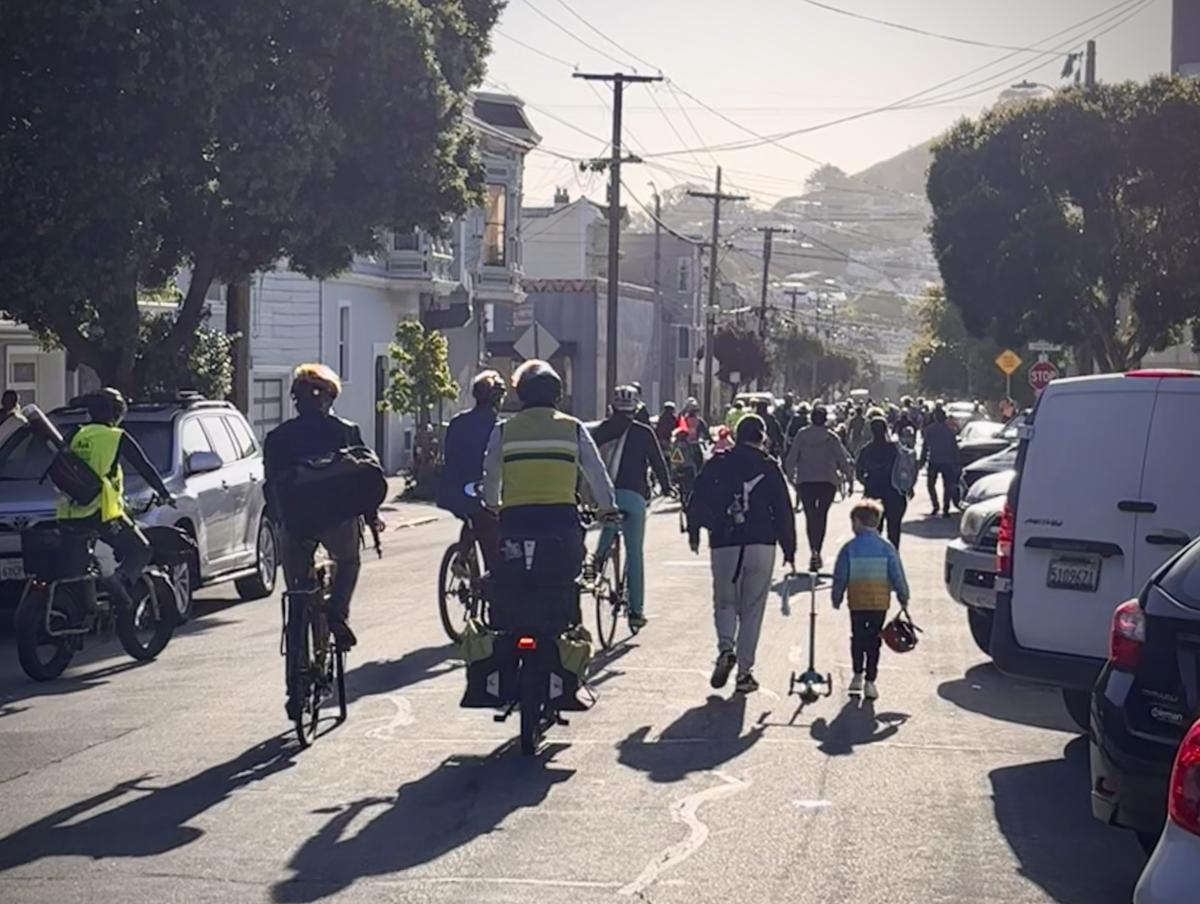 Adults and children on bikes and walking in the street