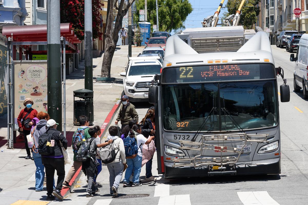 Children getting on a bus at an intersection.