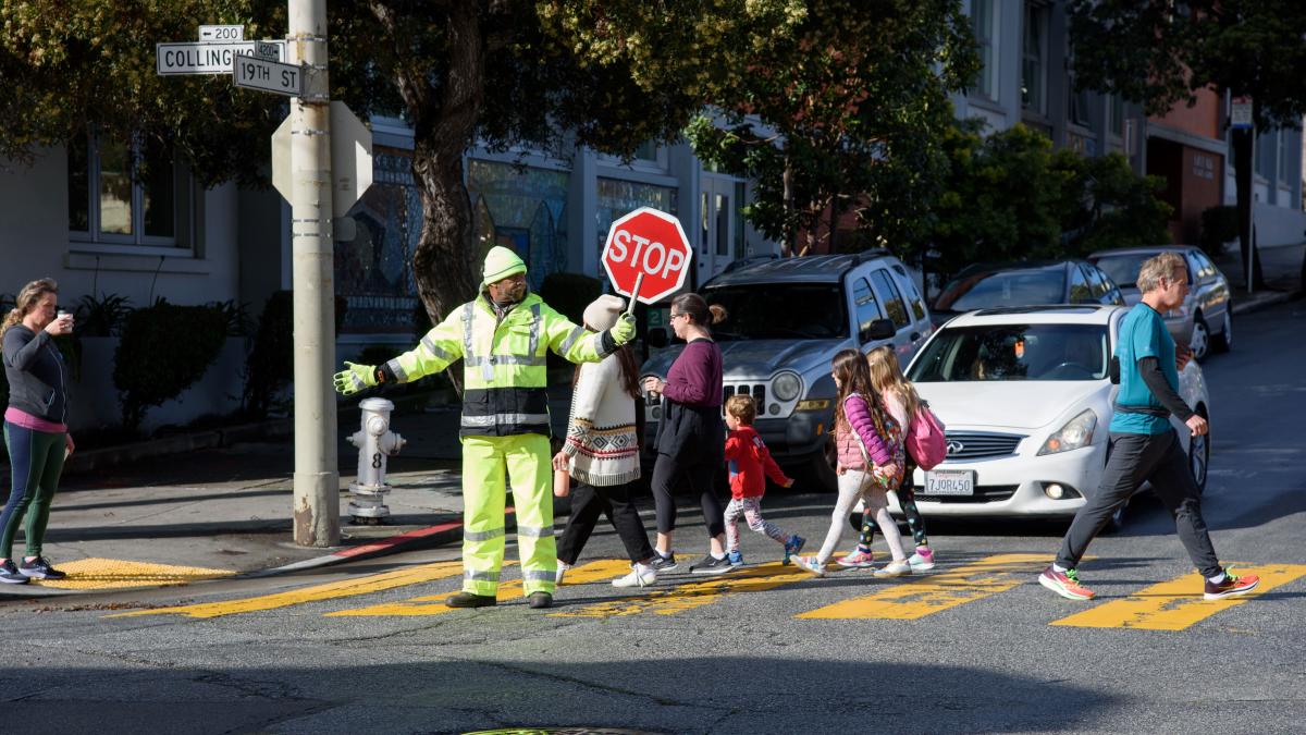 A crossing guard helps students and adults get across the street.