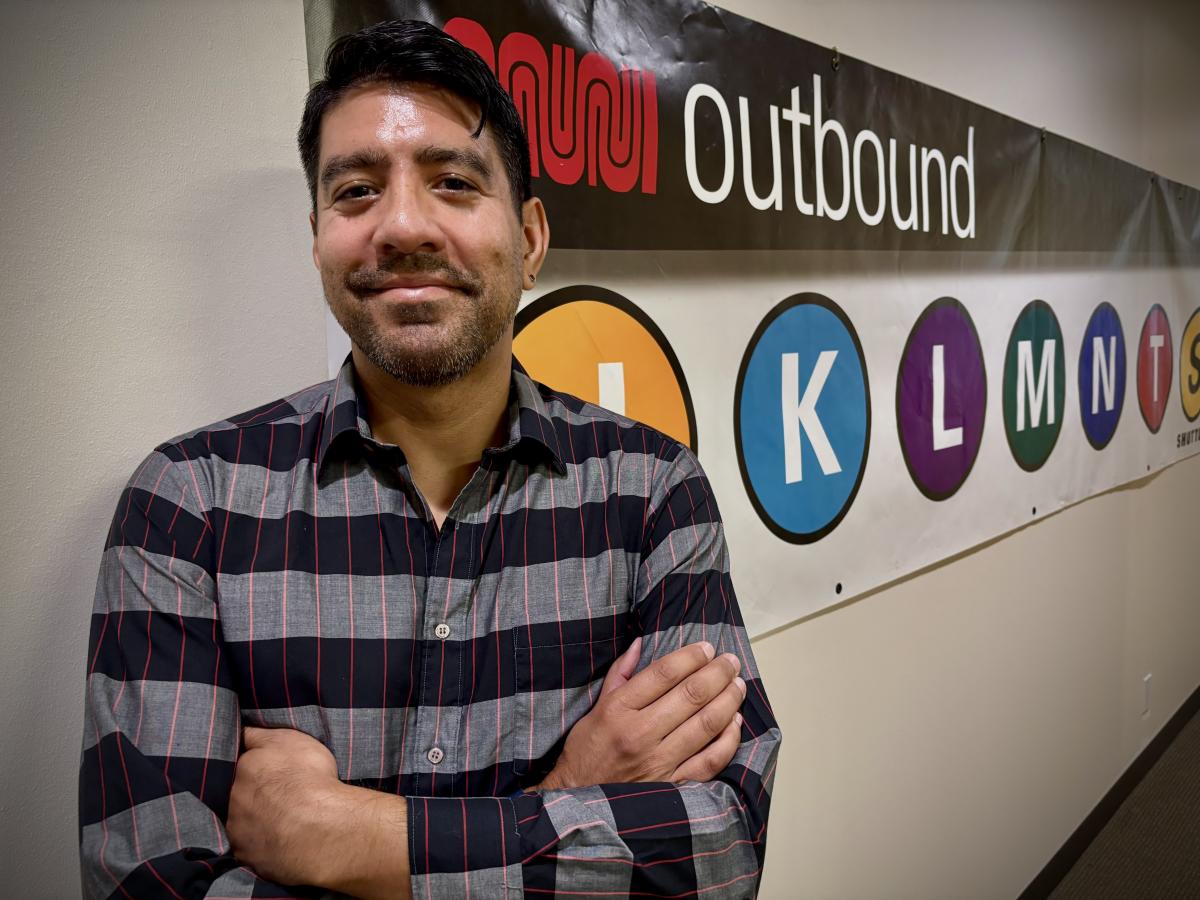 A person standing in front of a sign with large letters on it.