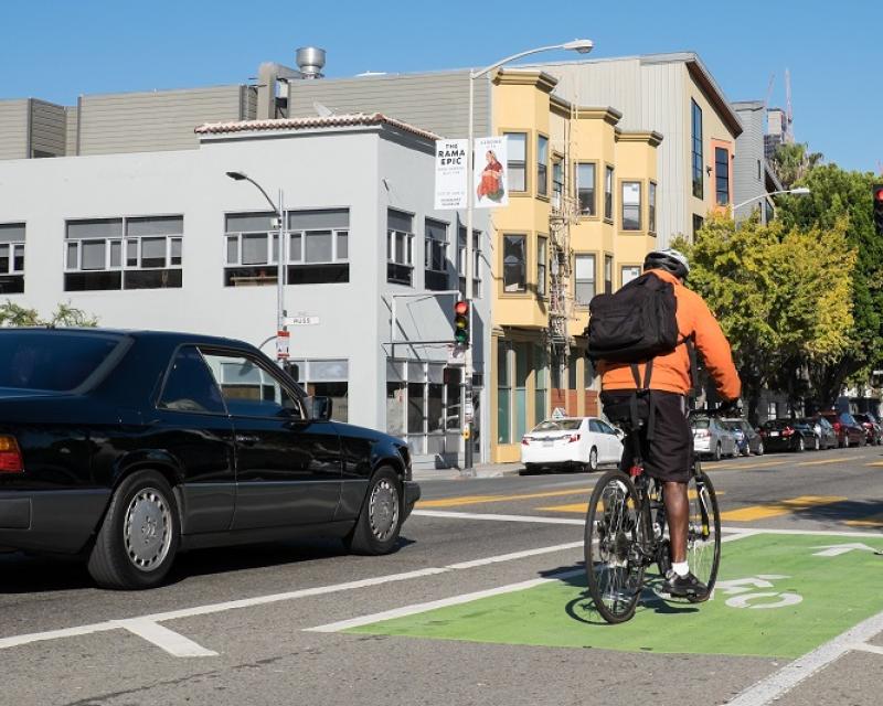 And man on bike and car traffic travel on Folsom Street at Russ Street.