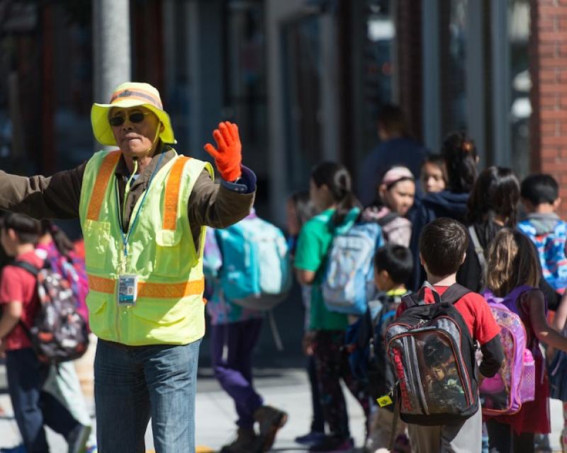 Crossing guard holding stop sign as students and parents cross the street.