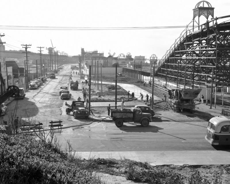 Black and white photograph looking south from Balboa and La Playa streets at construction of bus terminal in 1949.  To the right is a wooden amusement ride in Playland at the Beach amusement park.