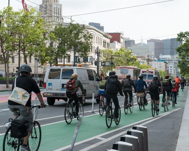 Group of bicyclists in a protected bike lane going east on Market in the afternoon