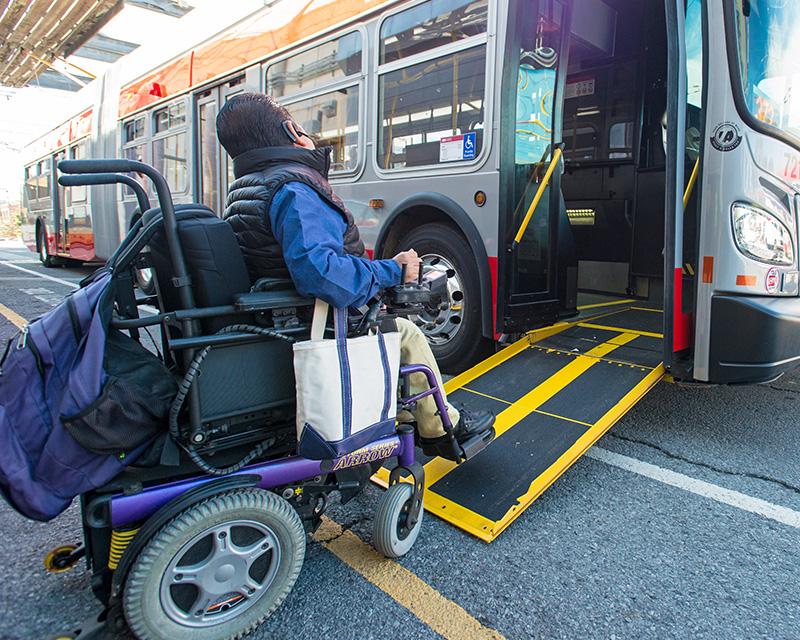A wheelchair user boards a Muni bus