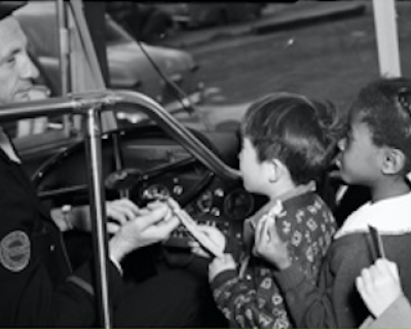 Bus driver greeting children as they board and pay their fares