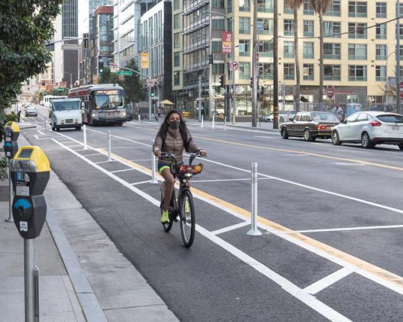Image shows woman biking down new protected bike lane 