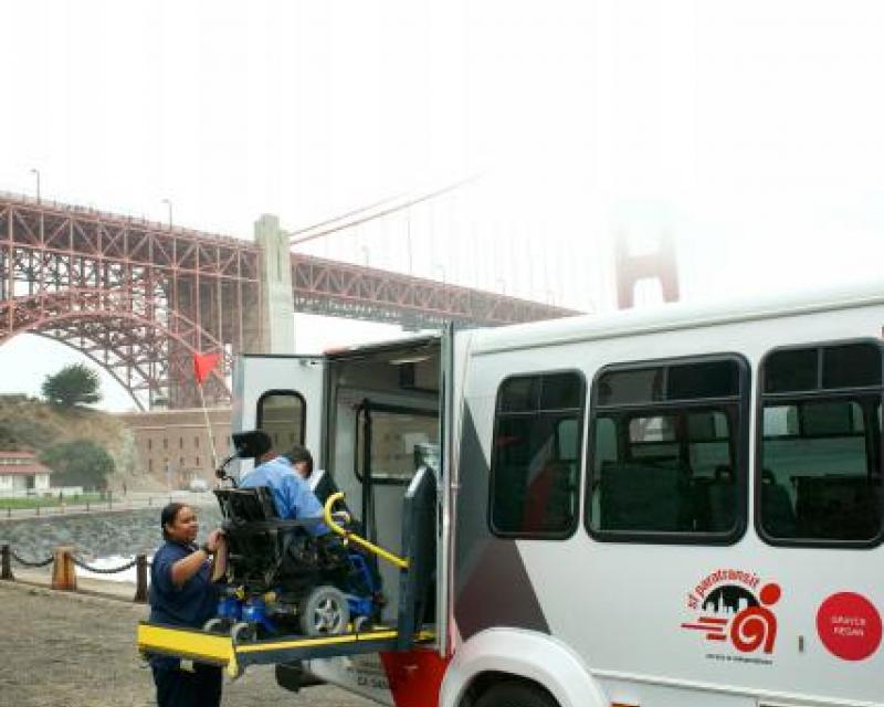 Paratransit staff helps customer onto a San Francisco Paratransit Bus at Fort Point