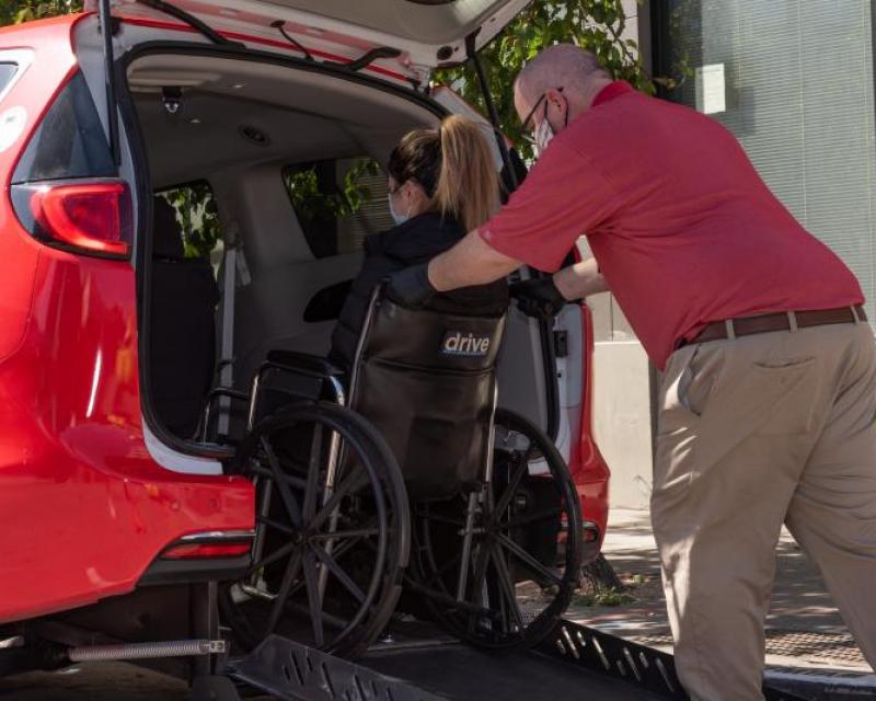 Taxi Driver Helping Passenger Using a Wheelchair into Ramp Taxi