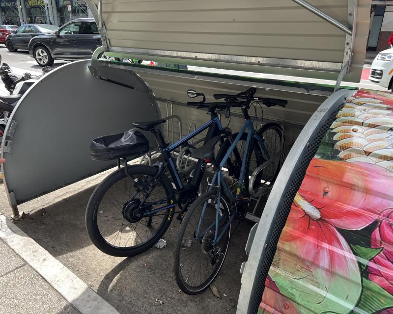 SFMTA’s new bikehangar at 4th & Minna streets with bikehangar door open & two bikes parked inside. 