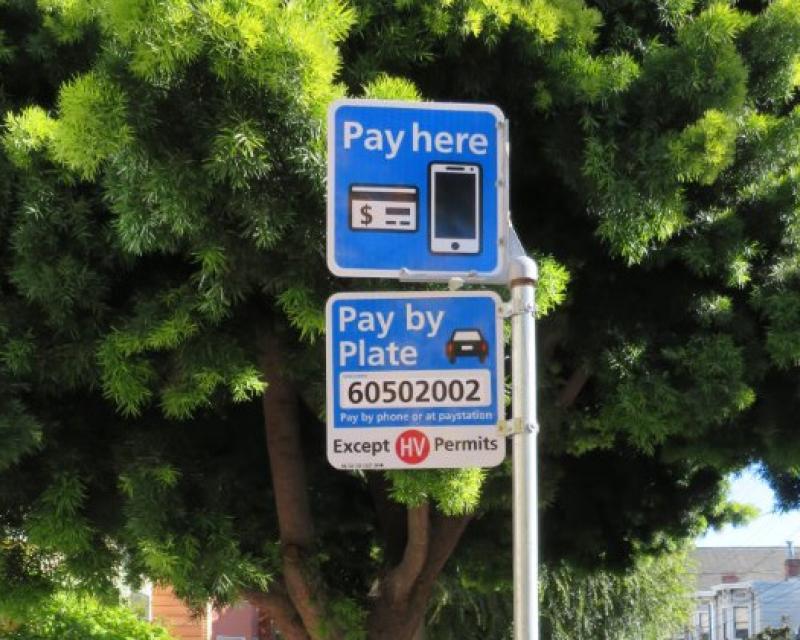 Blue Pay here parking sign in a residential neighborhood.