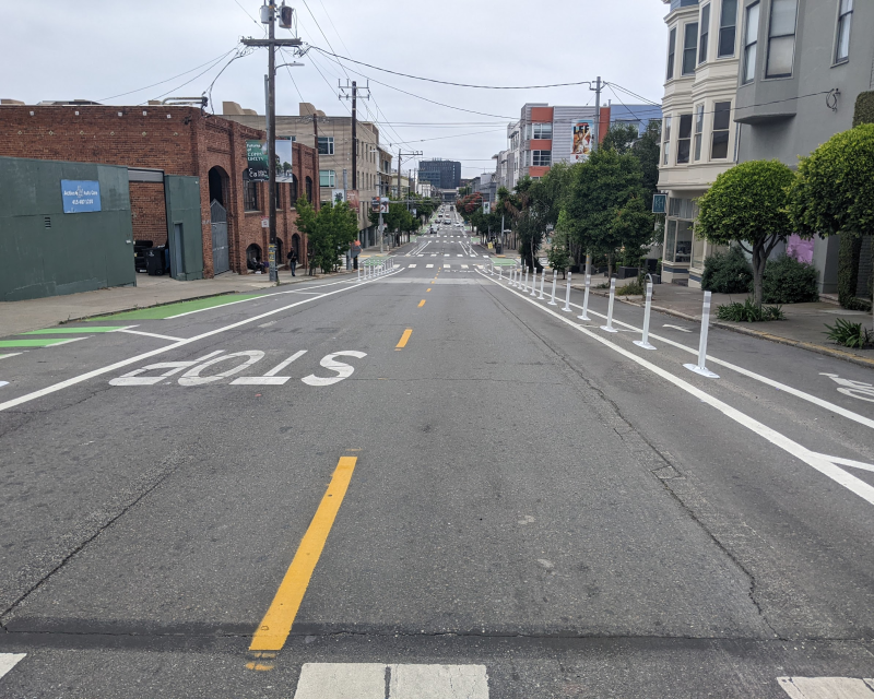 Vista hacia el este en 17th Street con Vermont Street que muestra el proyecto de construcción rápida completado, incluidos carriles para bicicletas separados por delineadores a cada lado de la calle.