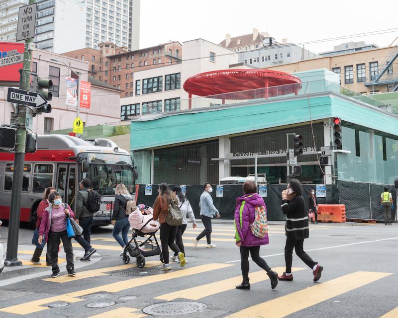 A photograph of the 30 Stockton passing the Chinatown-Rose Pak metro station on Stockton Street in San Francisco with pedestrians crossing the street. 