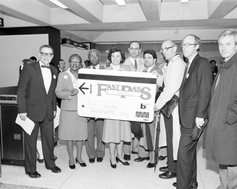 Archival photo in black and white that features former San Francisco Mayor Dianne Feinstein in Civic Center Station helping to promote a type of Fast Pass along with other officials at a press conference.