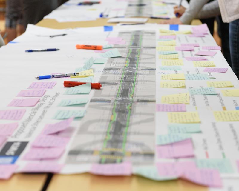 A close-up image of sticky notes with suggestions on a long print-out of the proposed side-running lanes from a Valencia open house. There are several dozen sticky notes visible, as well as pens, markers and highlighters..