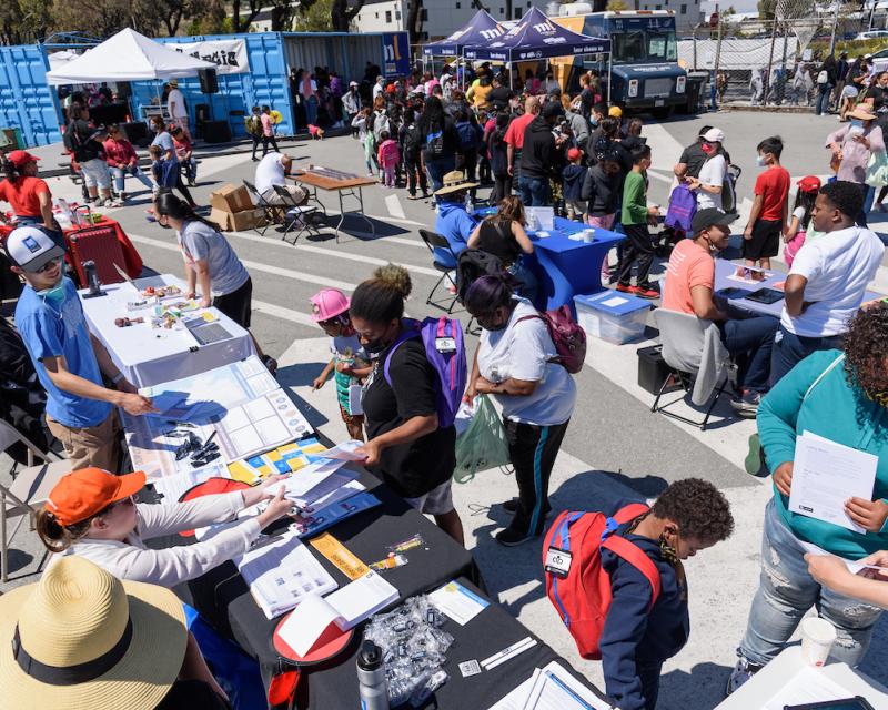 Overhead view of an outdoor public event featuring SFMTA staff tabling and connecting with local residents and others. 