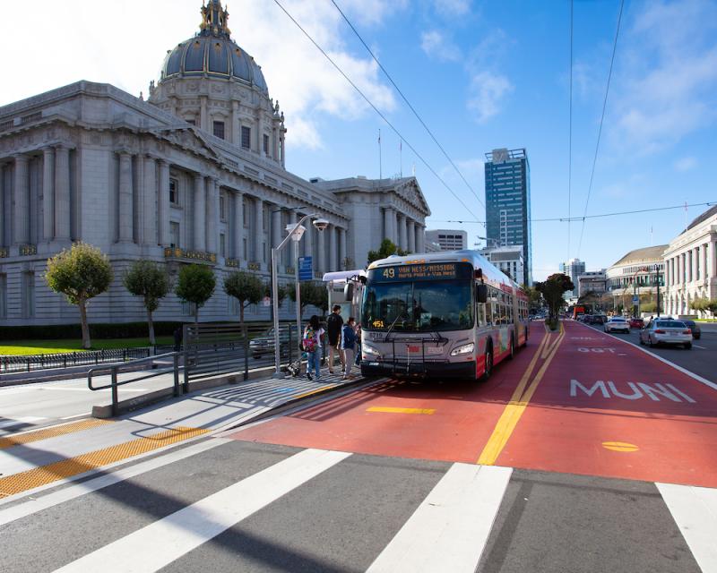 A 49 bus stops in front of San Francisco City Hall. A few passengers board.