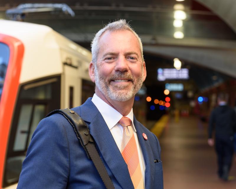 Jeff Tumlin stands on the West Portal Station platform as a train stops nearby.