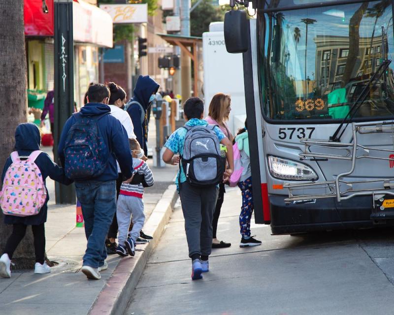 Several people walk toward a Muni bus to board. 