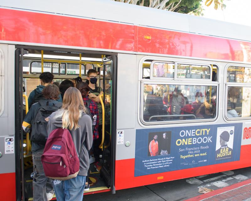 People wearing back packs board a bus. 