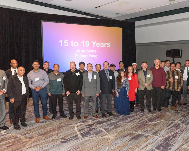 A group of our honorees at the 2024 Safe Driver Awards pose for a photo in front of a projector screen.