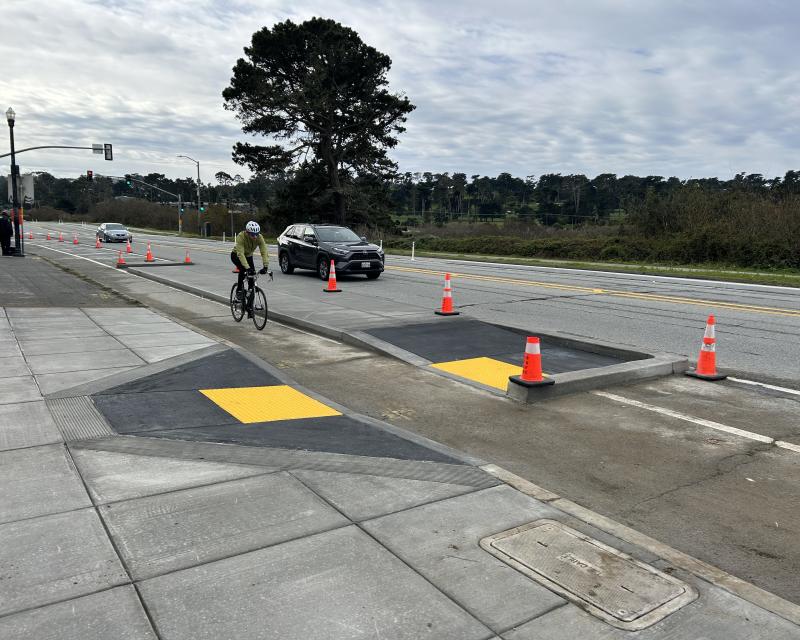 Bicyclist on completed bikeway protected by transit boarding island 