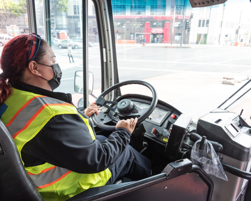 A Muni operator wearing a mask drives on the street.