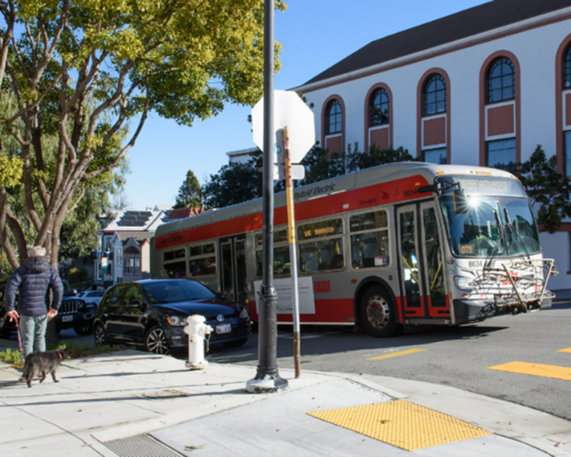 Photo of a flag stop with a bus stopped in the travel lane. 