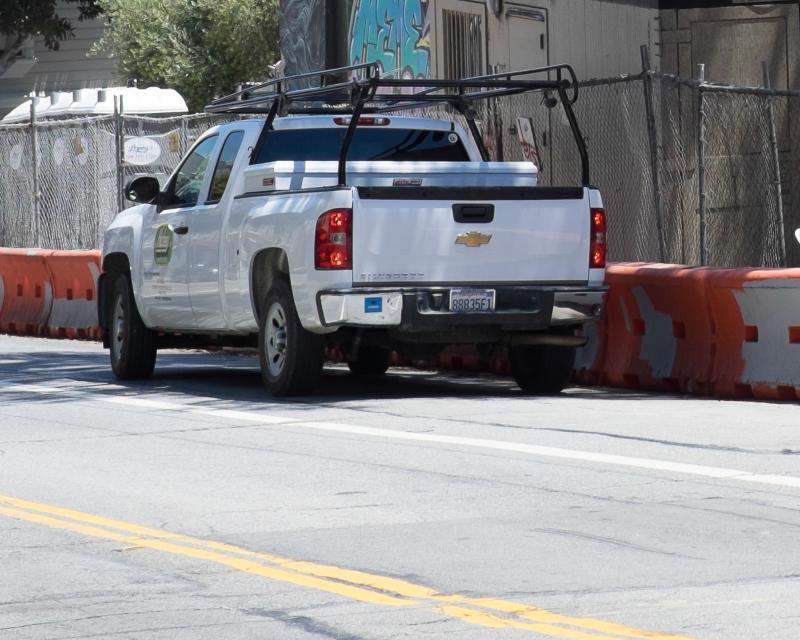 white pickup truck parked outside construction zone with contractor parking permit sticker on bumper