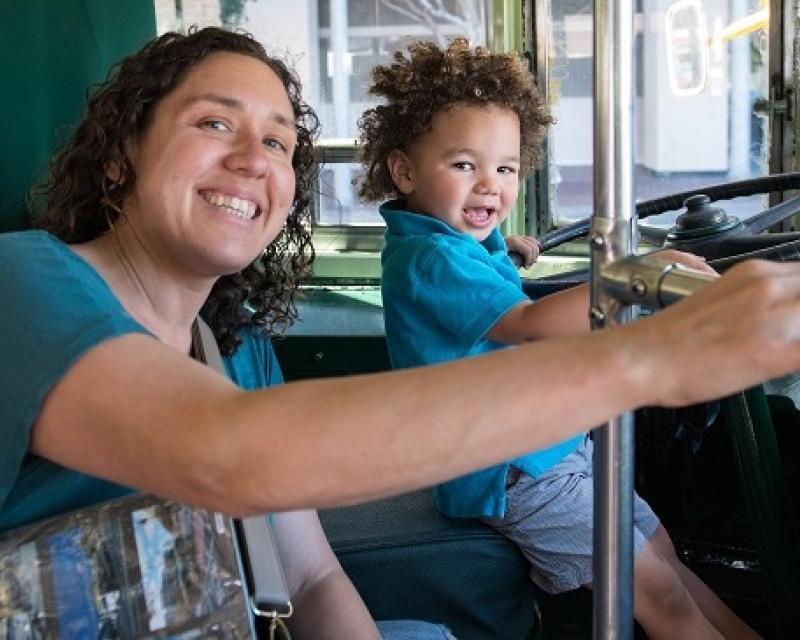 A child sitting in the operator's seat of a streetcar.